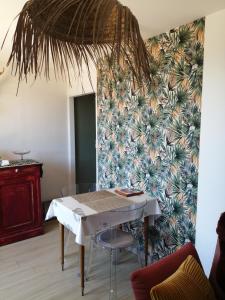 a dining room with a table and a tropical wallpaper at Chalet Dionysos in Murat-le-Quaire