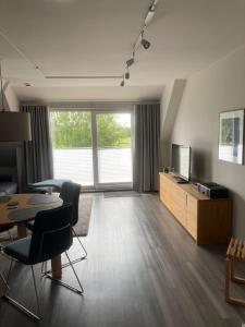 een woonkamer met een televisie en een tafel en stoelen bij Oasis 07 in Cuxhaven