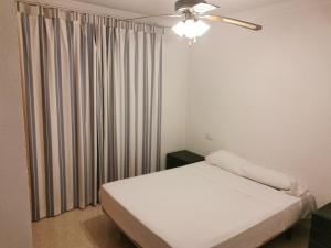 een kleine slaapkamer met een wit bed en een raam bij Estudios privados en Villa con piscina privada in Els Poblets
