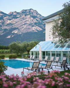 una piscina con sillas y una montaña en el fondo en Hotel Al Maso, en Riva del Garda