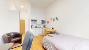 sypialnia z łóżkiem i krzesłem oraz kuchnia w obiekcie Amazing Studio Apartment w Londynie