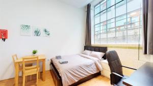 a bedroom with a bed and a desk and a window at Amazing Studio Apartment in London