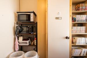 a microwave sitting on a shelf next to a door at Bed&Cafe Onzo オンゾー in Onomichi