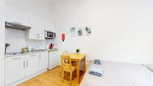 kuchnia z białymi szafkami i stołem w pokoju w obiekcie Amazing Studio Apartment w Londynie