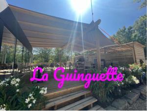 Una terraza de madera con un dosel con las palabras la guivreride en Paris Camping Ile du Roi, en Triel-sur-Seine