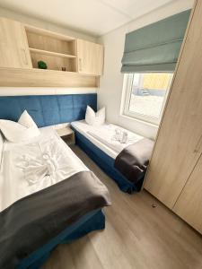 2 Betten in einem kleinen Zimmer mit Fenster in der Unterkunft Chalet am See in Wackersdorf