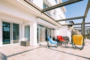 une terrasse avec des chaises et des fenêtres sur une maison dans l'établissement Chic Villa w Patio Pool 3 min to Beach in Bodrum, à Gundogan