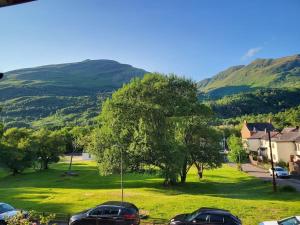 two cars parked in a field with mountains in the background at Kinlochleven Holiday Home in Kinlochleven