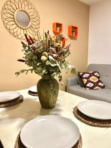 un jarrón de flores sentado en una mesa con platos en Apartamento La Rosa - RECIÉN REFORMADO, en Córdoba