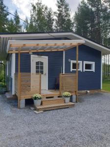 ein kleines blaues Haus mit einer Veranda und einer Terrasse in der Unterkunft Simola in Pihtipudas