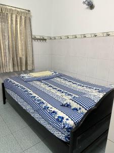 a bed with a blue and white quilt on it at Cát Phượng Motel in Phan Thiet