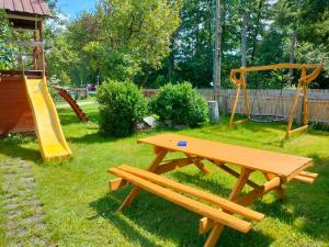 a wooden picnic table with a swing and a playground at Pokoje Gościnne Danusia in Karwieńskie Błoto Drugie
