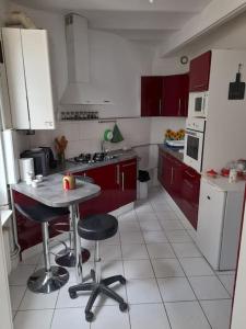 een keuken met rode kasten en een tafel en stoelen bij Bienvenue in Auxerre