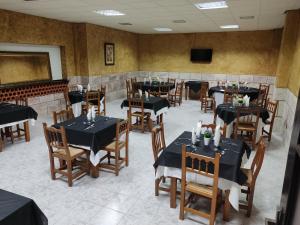 a restaurant with black tables and chairs and a television at Las Talliscas in Casas de Don Gómez