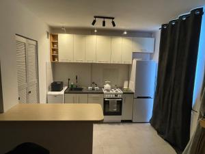 a small kitchen with white appliances and a table at Klimatyczna kawalerka w centrum in Gdynia