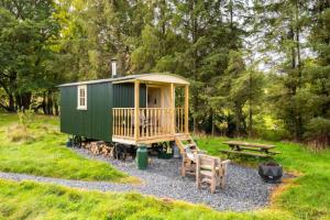 a green tiny house with a picnic table and a bench at Shepherds Hut at The Retreat in Oswestry