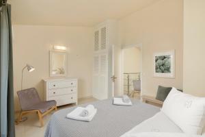 a white bedroom with a bed and a chair at Skales Villas in Almiros Beach