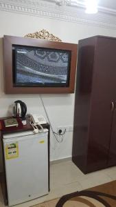 uma televisão numa parede ao lado de um frigorífico em Al Tawfik Plaza em Meca
