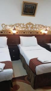 um quarto com 2 camas e lençóis brancos em Al Tawfik Plaza em Meca