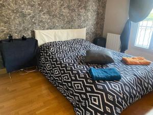 ein Bett mit einer schwarzen und weißen Bettdecke und Kissen darauf in der Unterkunft Appartement à Paris in Le Raincy