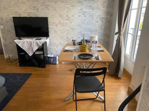 einen Tisch mit einem Stuhl und einen TV in einem Zimmer in der Unterkunft Appartement à Paris in Le Raincy