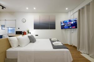 1 dormitorio con 1 cama grande y TV en la pared en Seaside Serenity: Charming Studio Flat, en Atenas