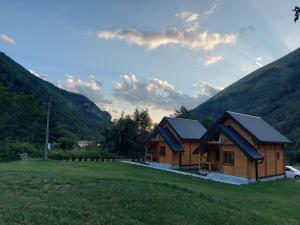 a cabin in a field with mountains in the background at Riverland Cottage 1 in Kolašin