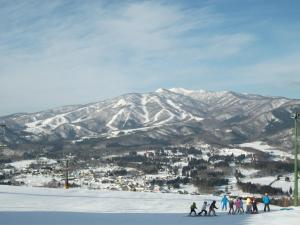 un groupe de personnes skier sur une montagne enneigée dans l'établissement 交流宿　星降る家　いこい, à Gujō