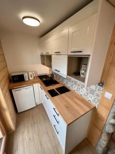 a small kitchen with white cabinets and wooden floors at Domek Olczyski in Zakopane
