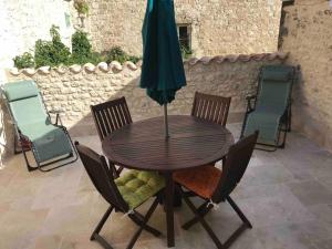 einen Holztisch mit Stühlen und einem Sonnenschirm auf einer Terrasse in der Unterkunft La Maison De La Tour Annex in La Sauvetat-du-Dropt