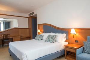 a bedroom with a white bed and a blue chair at Hotel Centrale in Sabaudia