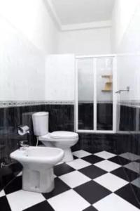 a bathroom with a toilet and a checkered floor at Maggona Beach Villa in Maggona West