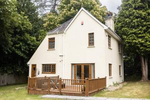 een wit huis met een houten terras bij Romantic Cottage in Plymouth