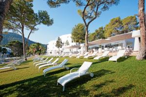 a row of white chairs sitting in the grass at Grupotel Ibiza Beach Resort - Adults Only in Portinatx