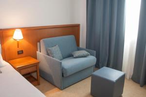 a room with a blue chair and a table and a lamp at Hotel Centrale in Sabaudia