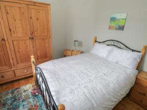 een slaapkamer met een bed en een houten kast bij 7 Aikenhead Terrace in Foxford