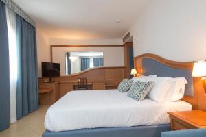 a bedroom with a white bed and a television at Hotel Centrale in Sabaudia