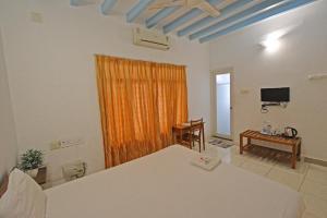 um quarto com uma cama e uma televisão em Villa Waves em Pondicherry