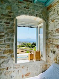 a bedroom with a window with a view of the ocean at Santa Maria Traditional Stone Studio in Santa Marina