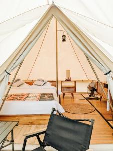 a tent with a bed and a chair in a room at PukuPods - Tent & Cabin in Tabanan