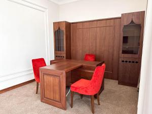 a dining room with a wooden table and red chairs at Reikartz Sote Tashkent in Tashkent