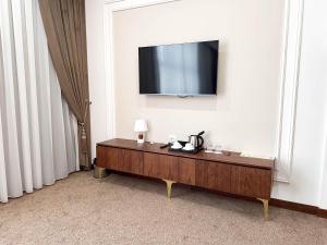 a room with a television on a white wall with a table at Reikartz Sote Tashkent in Tashkent