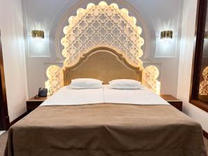 a bedroom with a large bed with a large headboard at Reikartz Sote Tashkent in Tashkent