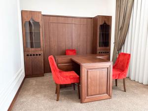 a wooden table with red chairs in a room at Reikartz Sote Tashkent in Tashkent