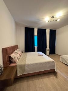 - une chambre avec un lit et une fenêtre avec des rideaux dans l'établissement Holiday apartaments, à Tirana