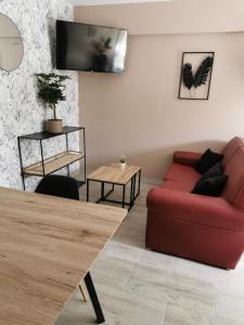 uma sala de estar com um sofá vermelho e uma mesa em La chaumière em Longues-sur-Mer