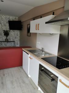 eine Küche mit weißen Schränken und einem Waschbecken in der Unterkunft La chaumière in Longues-sur-Mer