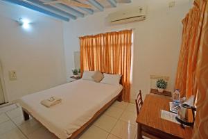 1 dormitorio con cama, escritorio y ventana en Villa Waves en Pondicherry