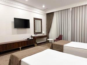 a hotel room with two beds and a flat screen tv at Reikartz Sote Tashkent in Tashkent