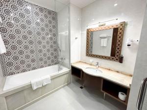 a bathroom with a sink and a tub and a mirror at Reikartz Sote Tashkent in Tashkent